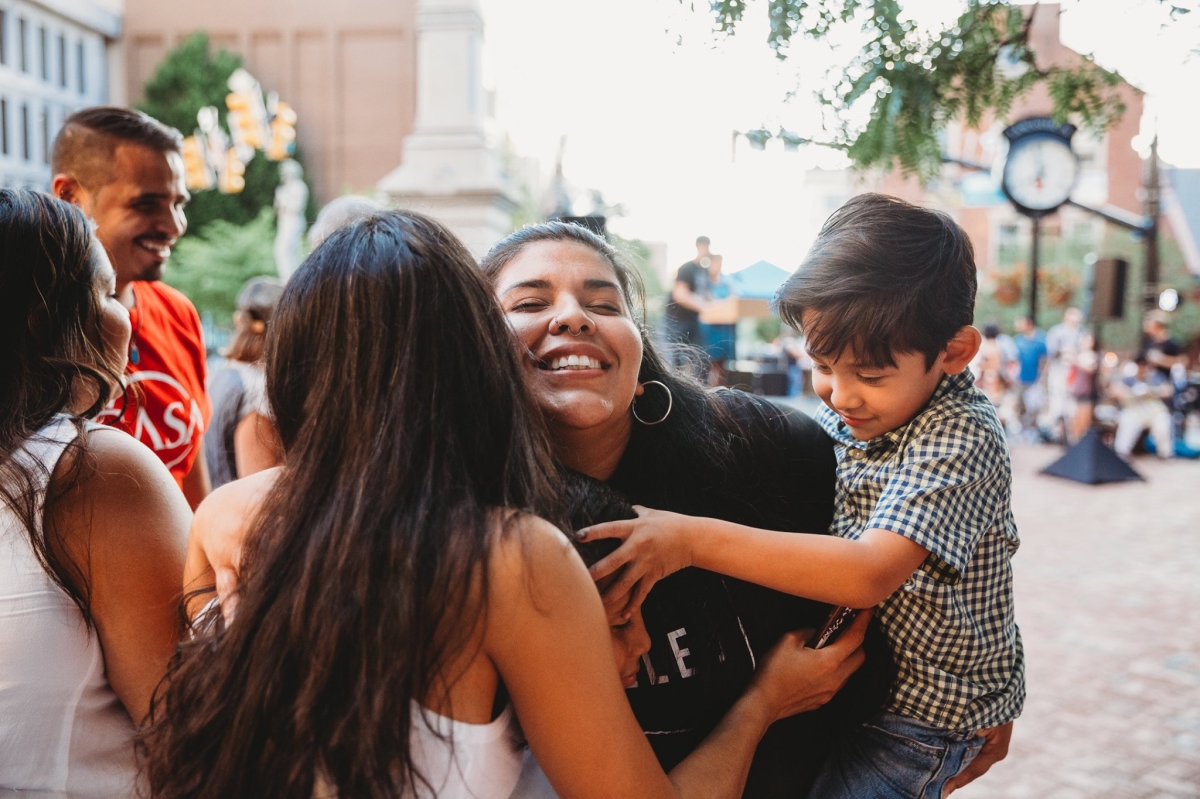 Two women enthusiastically embracing while holding two children.